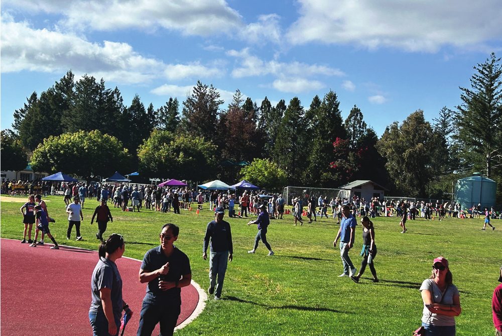 Runners and families on the field at a cross-country meet